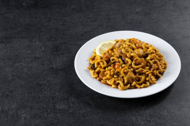 Traditional Spanish fideua on black stone background. Noodle paella. Copy space