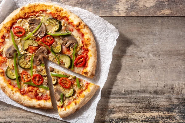 Vegetarian pizza with zucchini, tomato, peppers and mushrooms on wooden table. Top view. Copy space