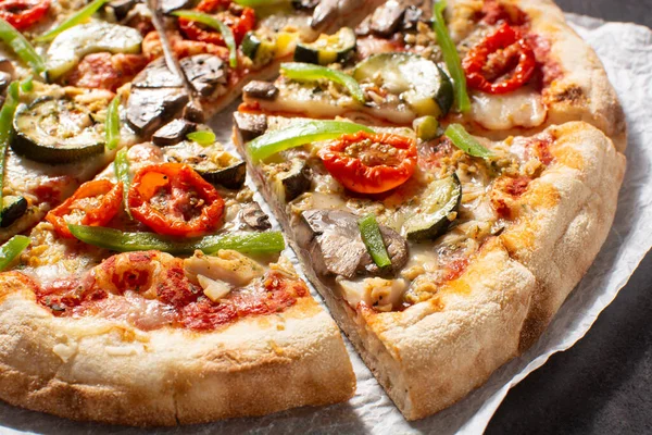 Vegetarian pizza with zucchini, tomato, peppers and mushrooms on wooden table. Close up