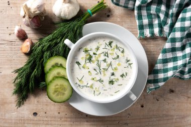 Bulgar taratör, ahşap masada kasede ekşi süt çorbası içiyor. Üst görünüm