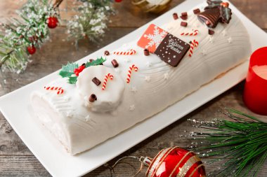 Tahta masa üzerinde Noel süsü olan beyaz çikolatalı Noel pastası.