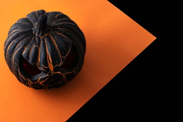 Black Halloween pumpkin on black and orange background. Copy space