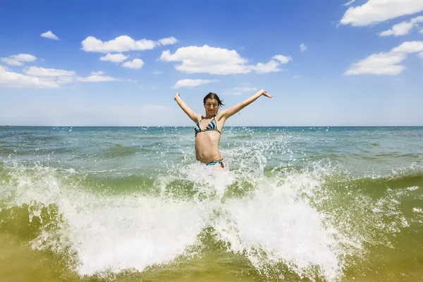 Girl jumping and splashing in the waves of the sea — Stock Photo, Image