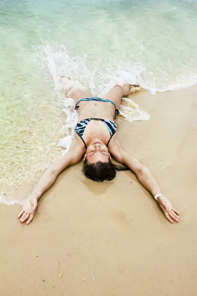 Tanned girl in bikini luxuriating in the waves on the beach — Stock Photo, Image