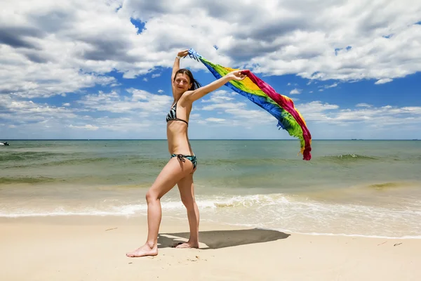 Chica bronceada en bikini posando en la playa con pareos de colores —  Fotos de Stock
