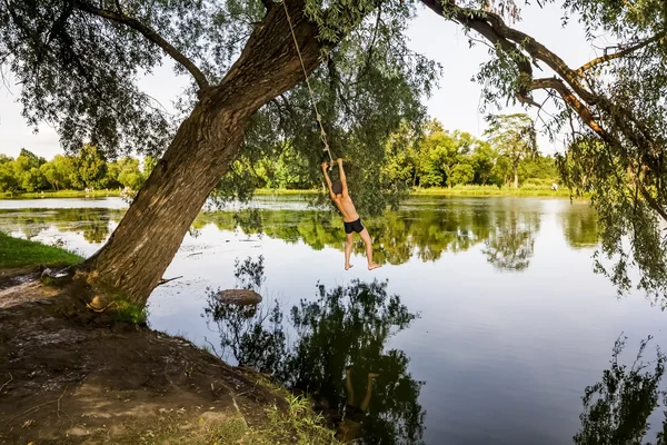 Мальчик прыгает в озеро с банджи-прыжком — стоковое фото