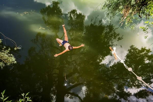 En pojke hoppar i en sjö med ett bungyjump — Stockfoto