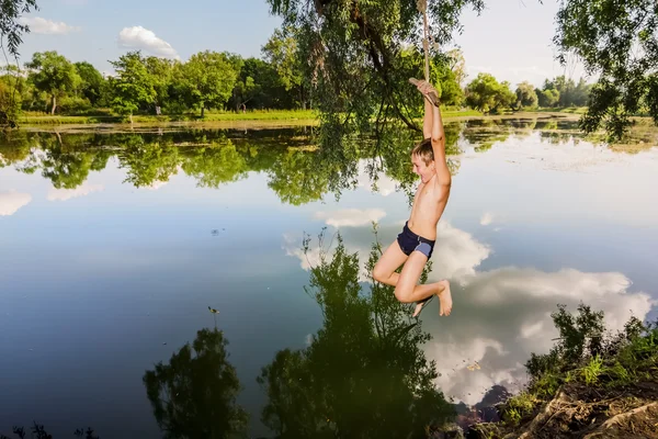 A boy jumps in a lake with a bungee jumping