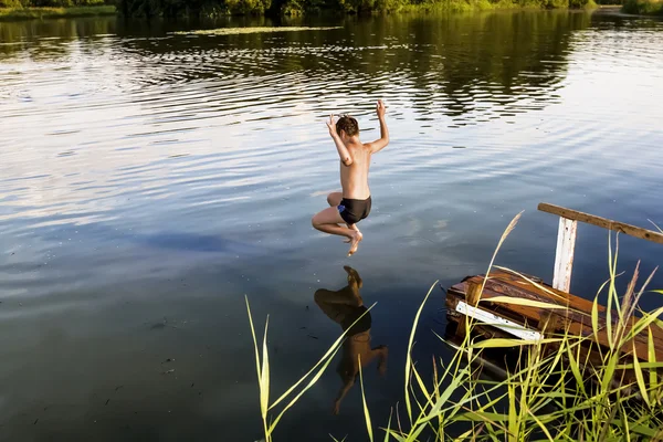 実行の開始と湖で少年ジャンプします。 — ストック写真