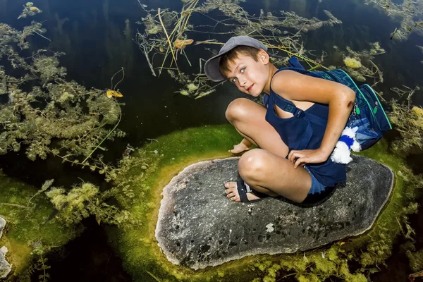 少年は湖のほとりに岩の上に座っています。 — ストック写真