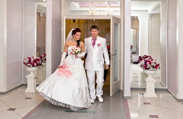 Bride and groom emerge from the doors of the Palace of weddings — Stock Photo, Image