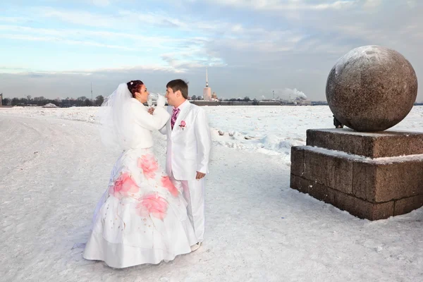 Newlyweds in wedding attire with glasses amid a winter of St. Petersburg at strelka of vasilievsky island — Stock Photo, Image