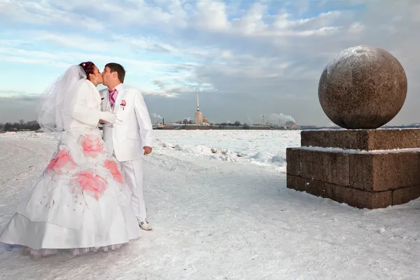 Newlyweds in wedding attire Kiss amid a winter of St. Petersburg at strelka of vasilievsky island — Stock Photo, Image