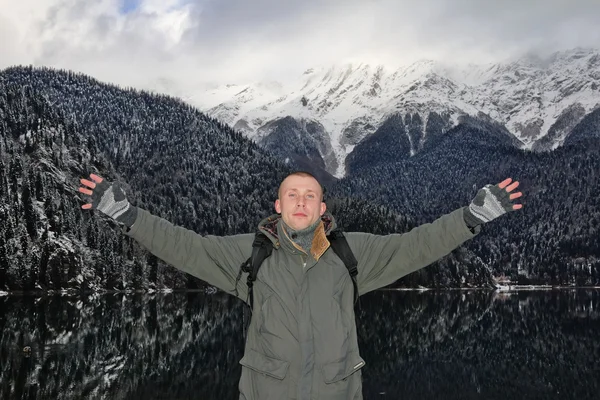 A man stands, arms outstretched, amidst the mountain panoramas