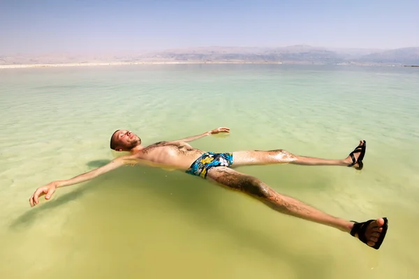 A man rests his hand on the water of the dead sea in Israel — Stock Photo, Image