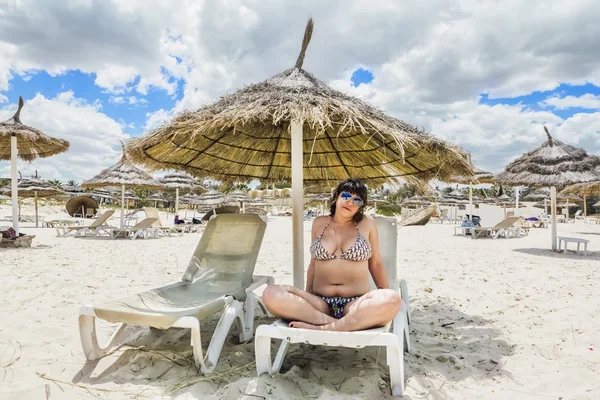 ビーチの傘の下に座ってビキニ日焼け少女 — ストック写真