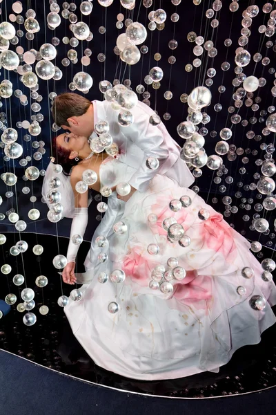 Nowożeńcy w strój ślub pozowanie w scenerii kulki szklane — Zdjęcie stockowe
