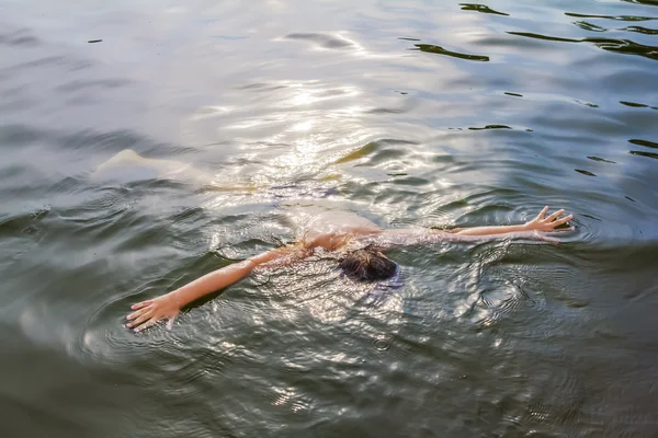 Pojken låg på vattnet i sjön på en sommardag — Stockfoto