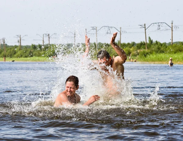 Un chico y una chica disfrutan salpicando en el lago — Foto de Stock