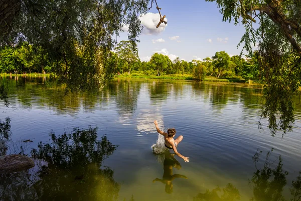 A boy jumps in a lake with a bungee jumping — Stock Photo, Image