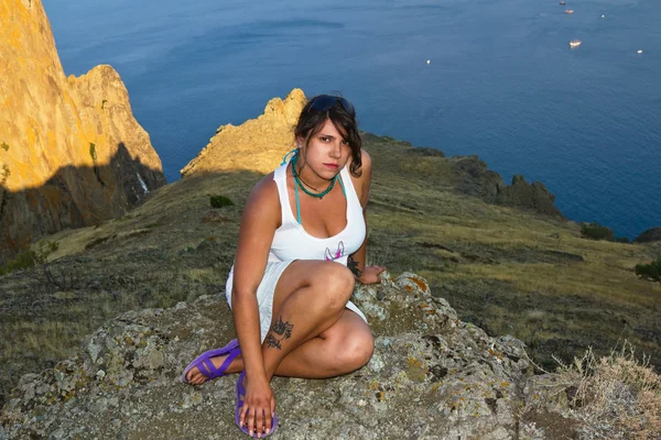 Ragazza si siede sul bordo di una scogliera sul mare — Foto Stock