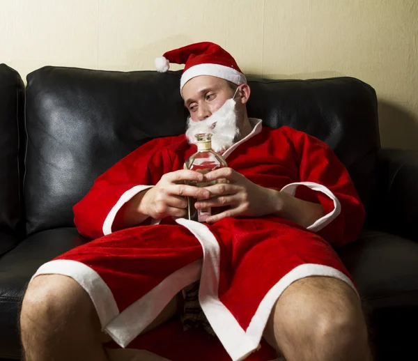 Babbo Natale ubriaco posa con una bottiglia di whisky — Foto Stock