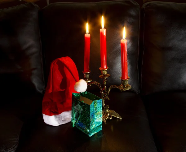 Chapéu de Papai Noel com presente e lustre com velas — Fotografia de Stock