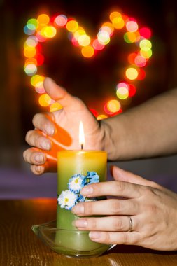 kadınların elleri üzerinde arka plan bokeh swee üzerinde yanan bir mum