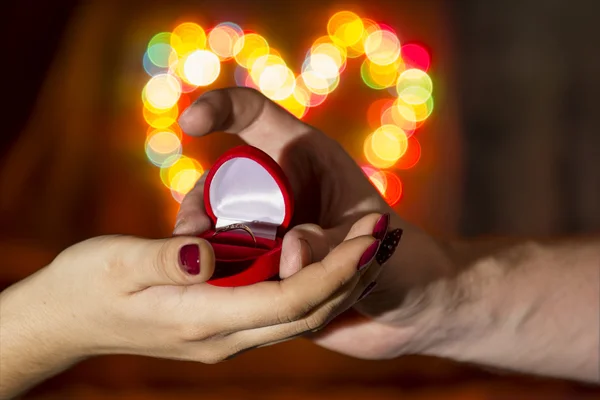 A man gives a woman a ring against the backdrop of a colorful he — Stock Photo, Image
