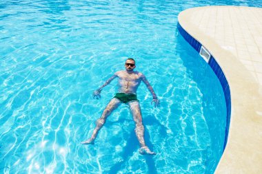 adamı havuza parlak güneşli bir günde yüzüyor.