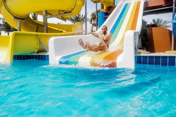 Egy férfi tekercs le a dombról egy aquapark egy ragyogó napsütéses napon — Stock Fotó