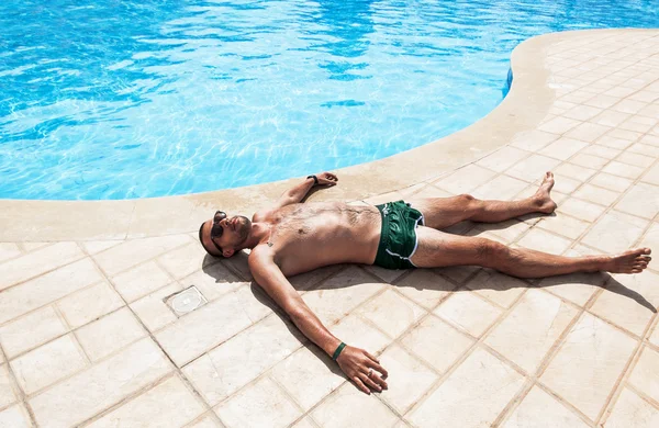 El hombre tomando el sol junto a la piscina —  Fotos de Stock