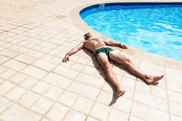 El hombre tomando el sol junto a la piscina — Foto de Stock