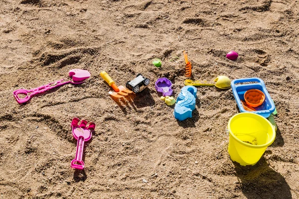 Buntes Kinderspielzeug im Sand am Strand verstreut — Stockfoto