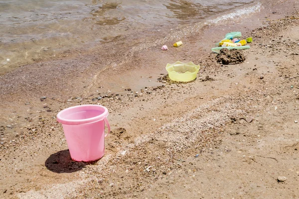 五颜六色的儿童玩具散落在沙滩上的沙子 — 图库照片