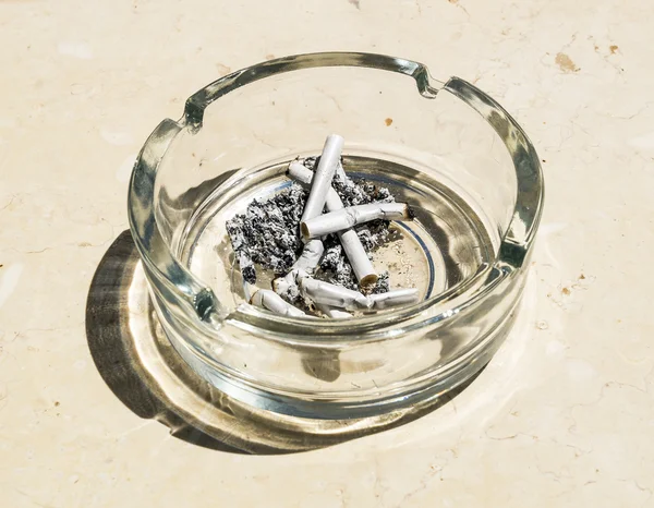 Cigarette butts from ash in the glass ashtray — Stock Photo, Image