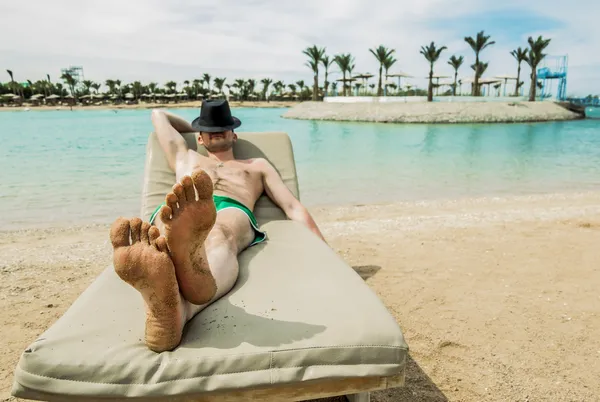 ビーチでサンラウン ジャーの上 sunbathes, 帽子の男は — ストック写真