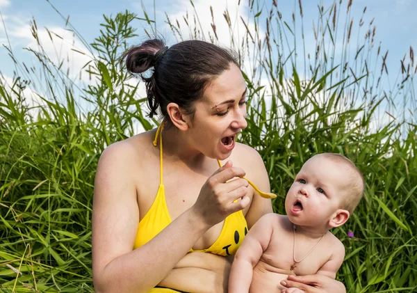 Joven madre alimenta a su bebé con una cuchara — Foto de Stock