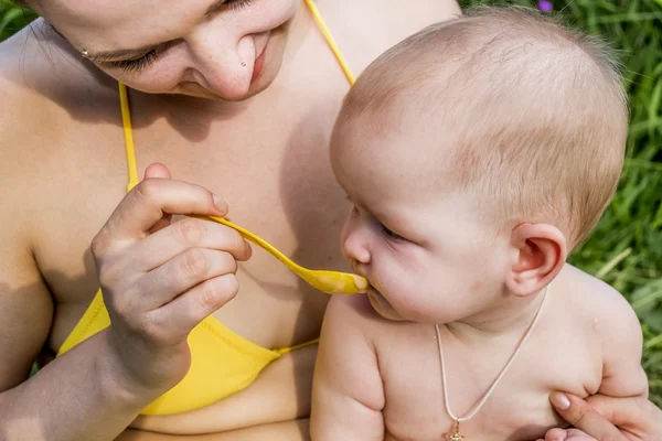 Joven madre alimenta a su bebé con una cuchara — Foto de Stock