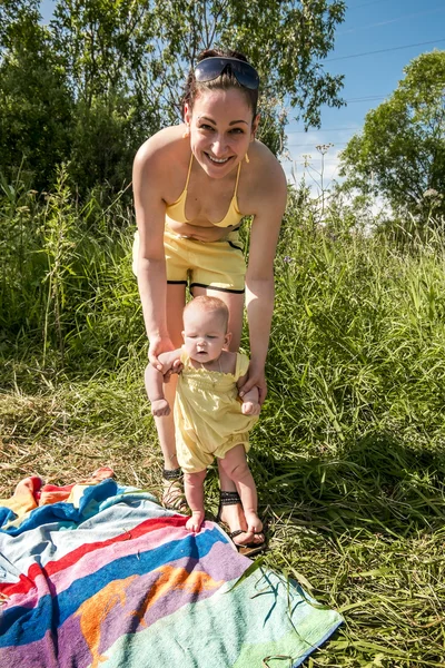 La madre joven ayuda al niño a dar los primeros pasos — Foto de Stock