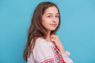 Ukrayna nakışlı giysileri olan 11 yaşındaki bir kızın portresi. Mavi arka planda bir kız.