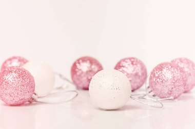 Noel teması. Beyaz ve pembe renkli Noel oyuncakları açık arkaplanda.