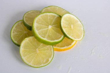 Limon, limon, beyaz arka planda sulu olgun turunçgil parçaları. Serinletici içecekler ve Mojito kokteylleri yapmak için gerekli malzemeler. Metnin için yer.
