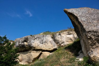Mavi gökyüzü arka planında izole bir kaya parçasında bulunan bir uçurum taşı..