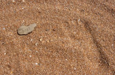 Sahildeki bir çakıl taşına yazılmış 2022 sayısının bir görüntüsü. Yılbaşı, Noel ve kış tatili konsepti.