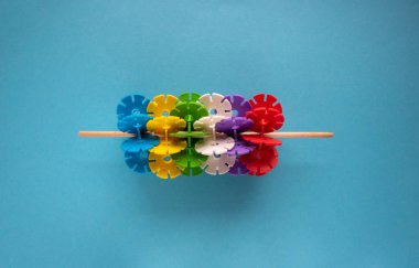 Mavi zemin üzerinde bir çubuk üzerinde tasarımcının çok renkli plastik parçaları figürü.