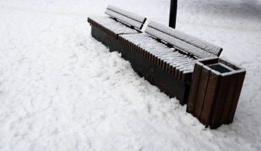 Parktaki ahşap bank, karla kaplı. Kışın başlangıcı..