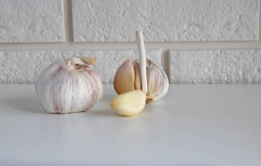 Beyaz mutfak masasında baş ve karanfil sarımsak..