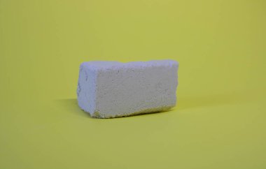 Stone podium on a yellow background. Product installation: broken stone slabs, white stone platform, placement of objects made of rough textured blocks.