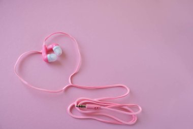 Pembe arka plandaki telefon için pembe kulaklık..